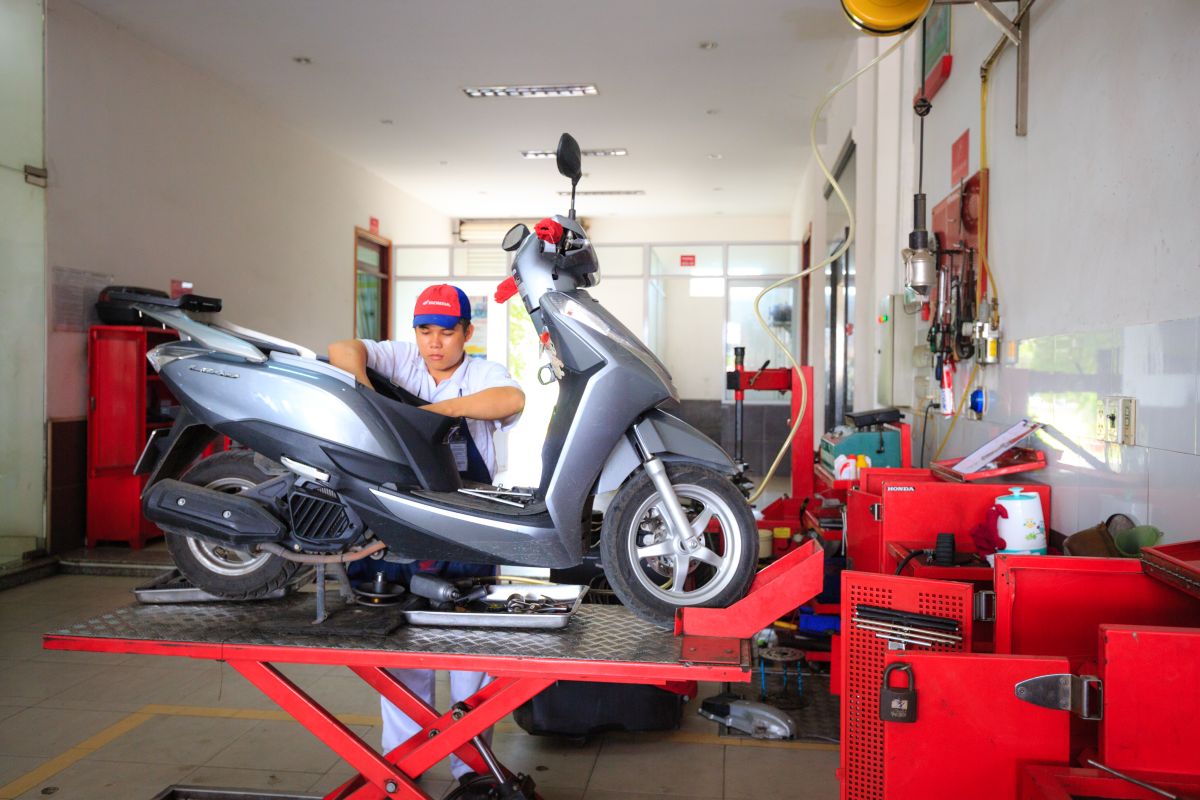 Mechanic performing maintenance on a scooter in a repair shop